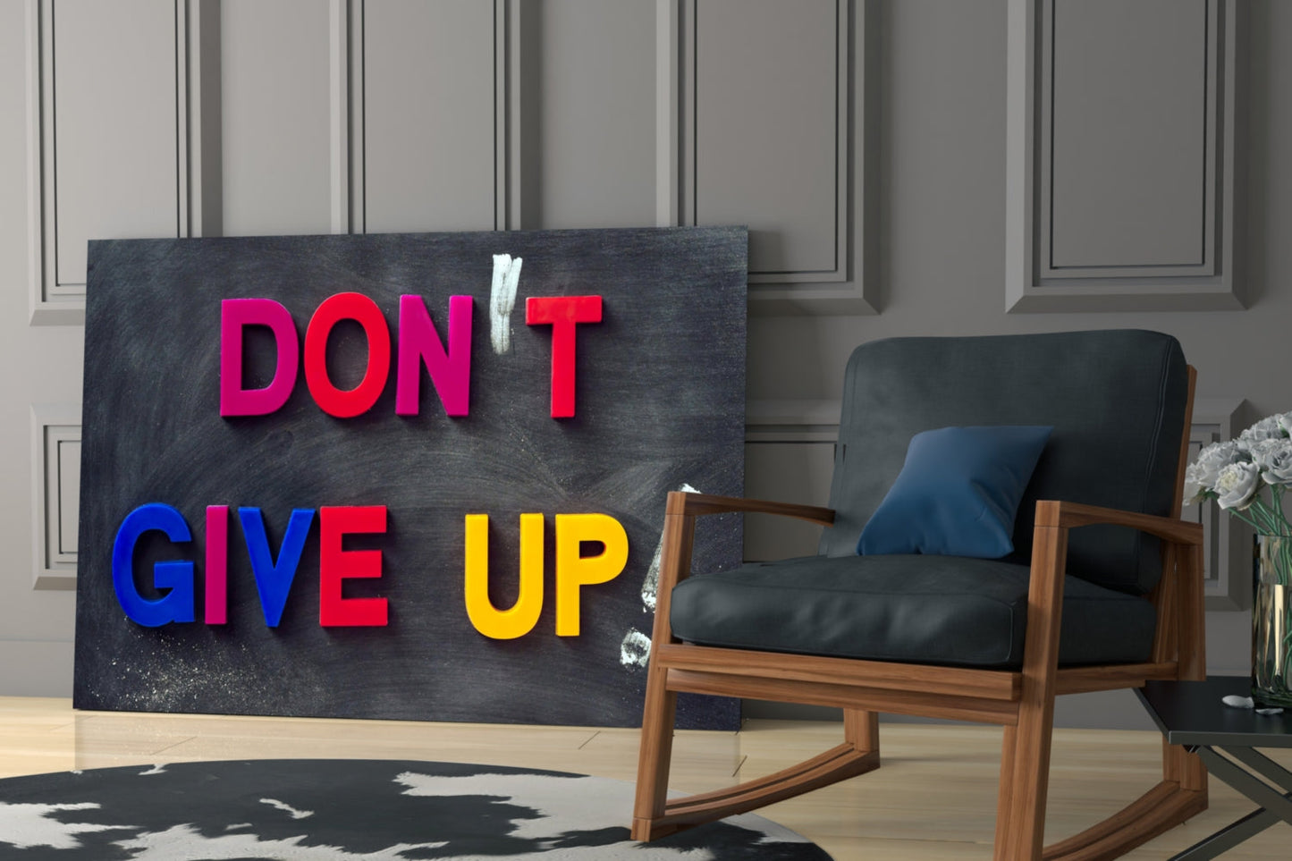 Black glass wall art with colorful 3D letters spelling "DON'T GIVE UP" displayed in modern interior beside wooden chair.