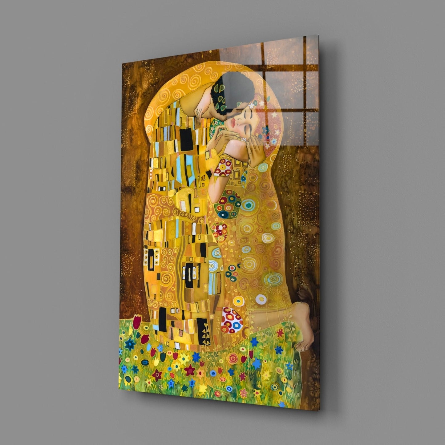 Glass wall art of Klimt's "The Kiss" mounted on gray wall, showing couple in gold robes against textured background with colorful flowers below.