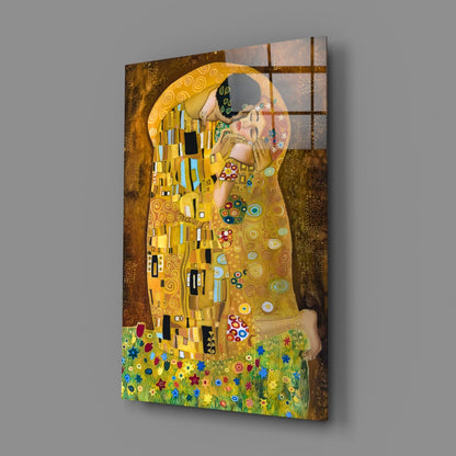 Glass wall art of Klimt's "The Kiss" mounted on gray wall, showing couple in gold robes against textured background with colorful flowers below.
