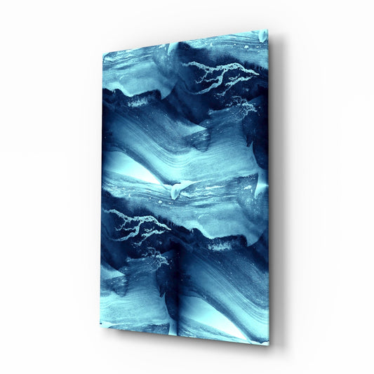 Angled view of blue glass wall art with layered wave patterns in light cyan and dark navy tones, mounted on white background.
