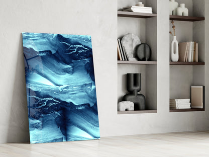 Blue Serenity Glass Wall Art leaning against white wall beside built-in shelving with decorative objects and books.