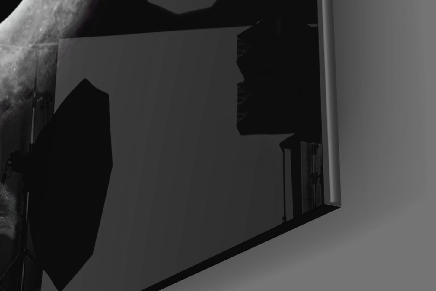 Black and white architectural photograph showing silhouetted glass wall art panel mounted on light interior wall with staircase visible behind.