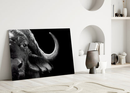 Black and white bison portrait glass art leaning against white wall in minimalist interior setting.