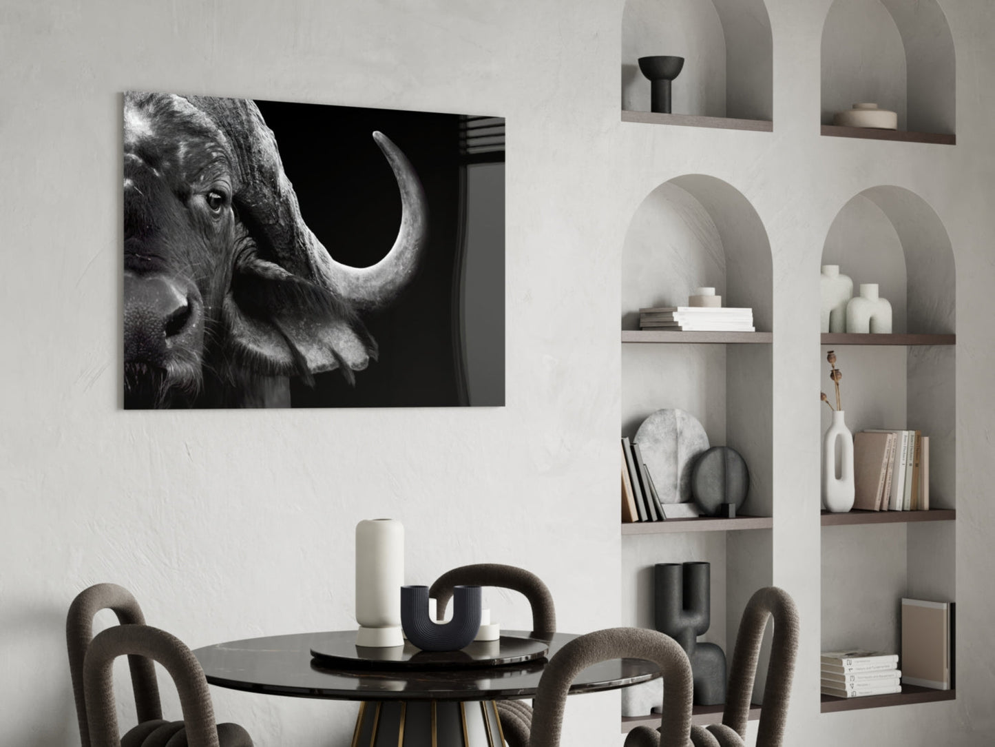 Black and white glass wall art of a bison's head in profile displayed above a dining table in a modern interior.