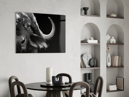 Black and white glass wall art of a bison's head in profile displayed above a dining table in a modern interior.
