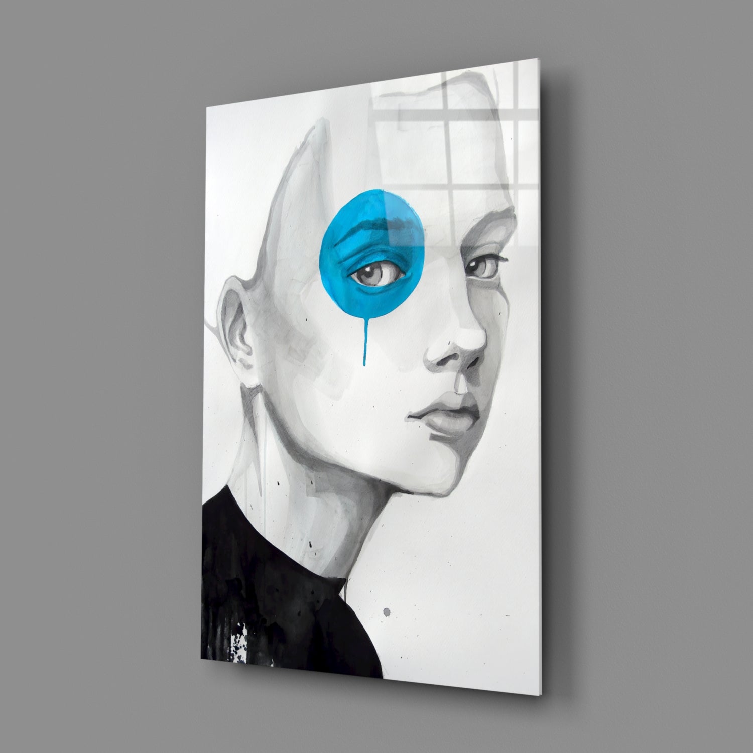 Glass wall art featuring a grayscale profile portrait with a bright blue circular overlay on one eye, displayed at an angled perspective against gray background.