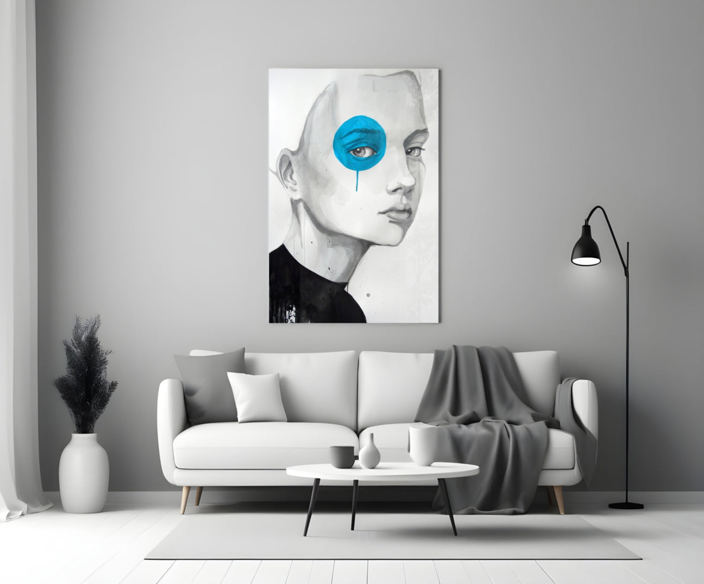Modern living room displaying framed glass wall art of a pencil-sketched face with bright blue circular eye detail above white sofa.