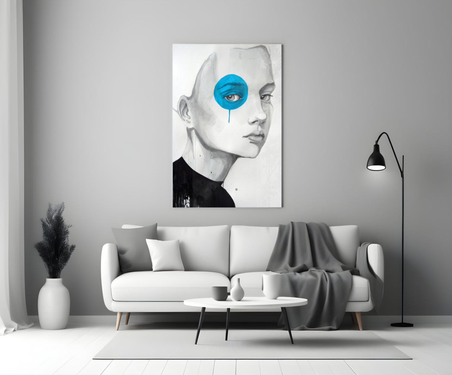 Modern living room displaying framed glass wall art of a pencil-sketched face with bright blue circular eye detail above white sofa.