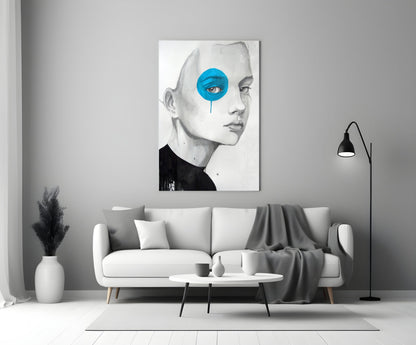 Modern living room displaying framed glass wall art of a pencil-sketched face with bright blue circular eye detail above white sofa.