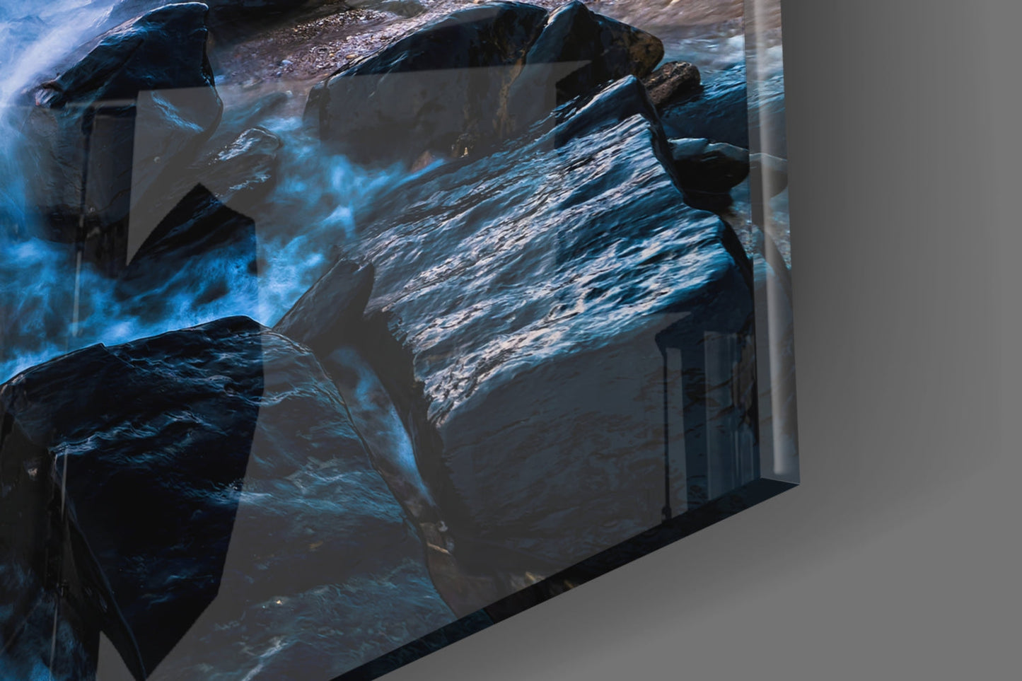 Angled view of Endless Sea Glass Wall Art displaying layered ocean rocks and blue water textures mounted on gray wall.