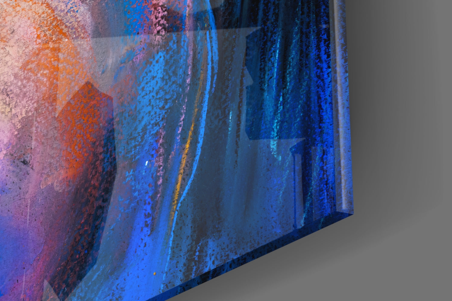 Close-up angled view of glass wall art showing layered blue, orange, and purple brushstroke textures with metallic accents.