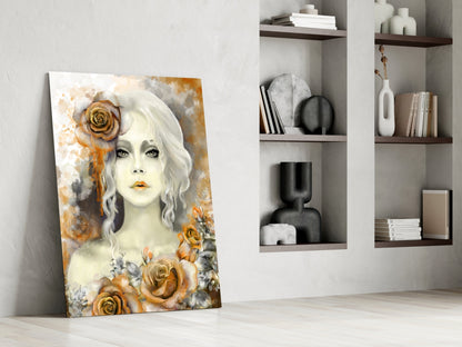Glass wall art leaning against white wall displays pale woman with white wavy hair surrounded by golden roses and watercolor background.