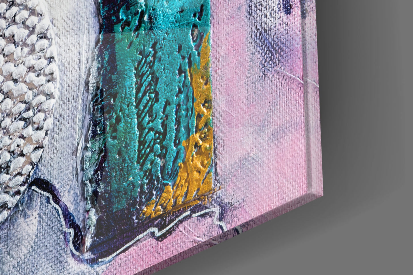 Close-up angled view of textured glass wall art featuring turquoise, pink, yellow, and white abstract layers with visible brushstroke details.