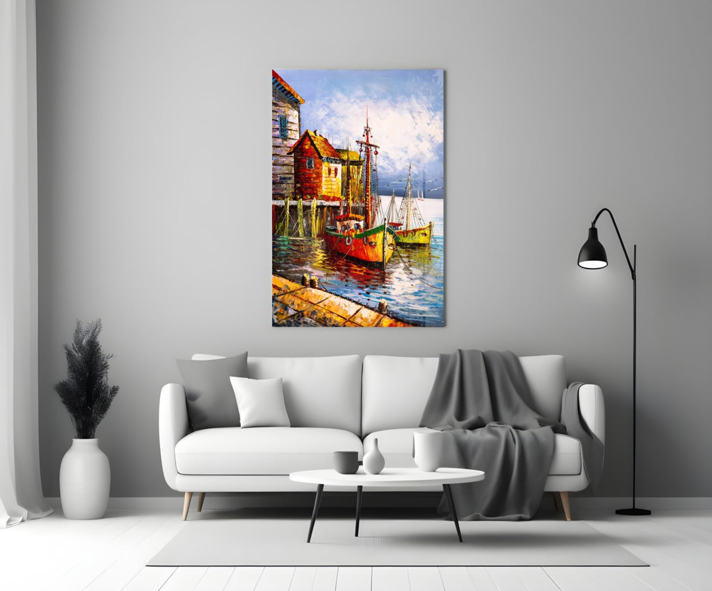 Colorful glass wall art depicting red and yellow boats docked at wooden structures by water, displayed above a white sofa in a modern living room.