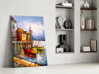 Colorful glass wall art depicting red and yellow fishing boats at a dock, displayed leaning against a white wall next to built-in shelving.