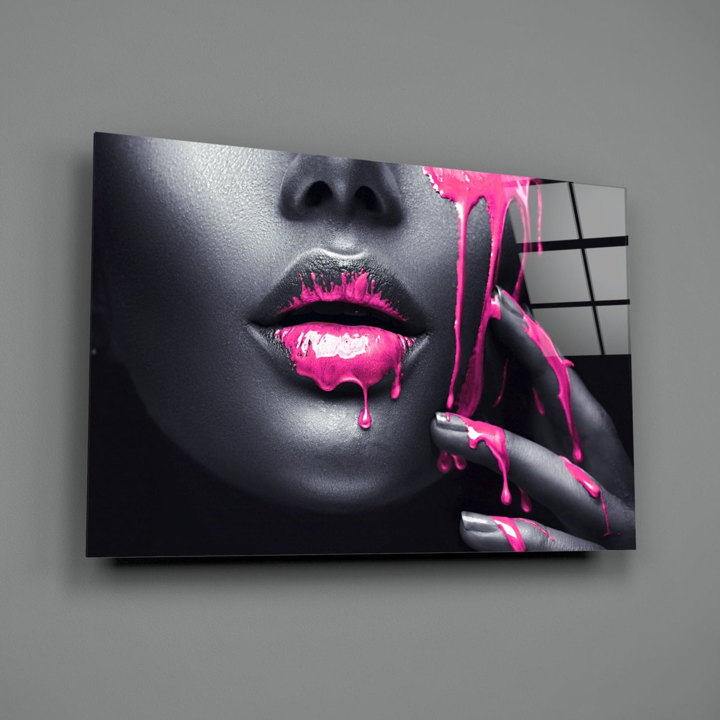 Glass wall art displaying close-up of woman's face with grayscale skin and vibrant magenta paint dripping from lips and fingers.