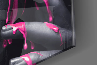 Close-up detail of pink painted glass wall art showing bright magenta paint drips and strokes on cylindrical glass forms against dark background.
