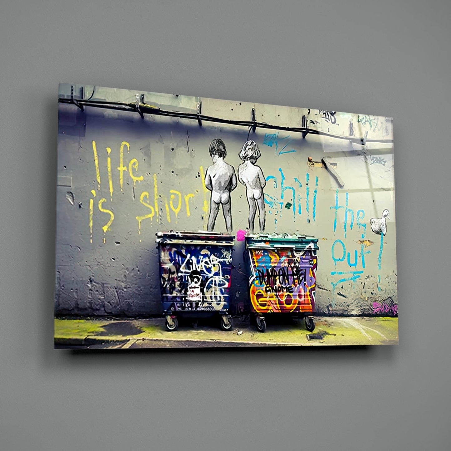 Glass wall art displaying street art of two nude figures above colorful graffitied bins with yellow and blue text reading "life is short" and "chilling out.