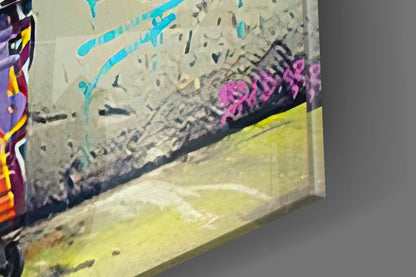 Glass wall art with colorful graffiti featuring cyan lines, pink lettering, and yellow-green sections, angled three-quarter view.