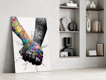 Canvas leaning against wall displaying colorful graffiti-filled peace hand gesture with black ink splatter effect, styled interior setting with shelving.
