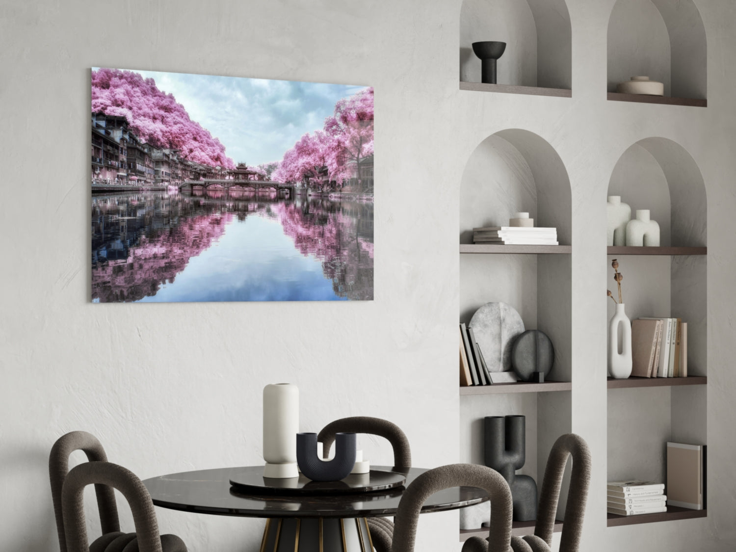 Glass wall art displaying a pink cherry blossom landscape with water reflection, installed above a dining table.
