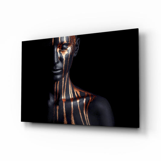 Portrait of a figure with black skin and bronze metallic drip paint streaks across face and torso against dark background.