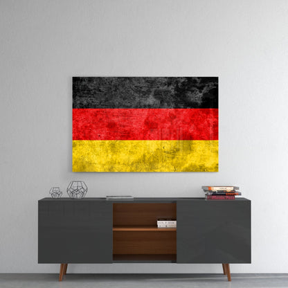 German flag glass wall art with black, red, and yellow horizontal stripes displayed above gray sideboard.