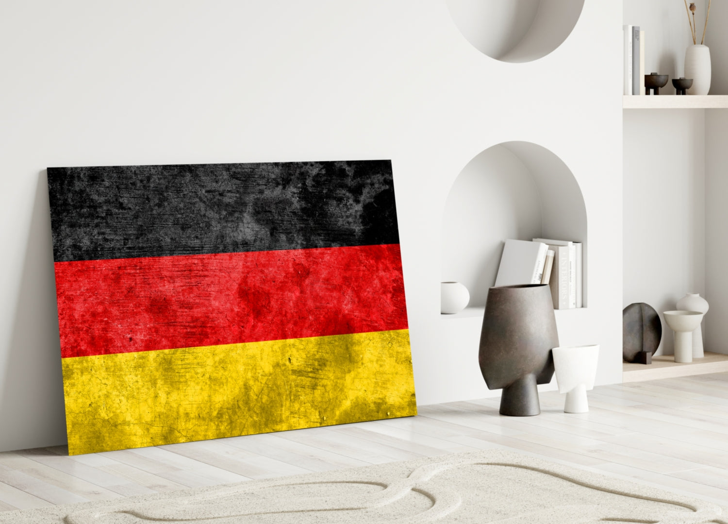 German flag glass wall art leaning against white wall in minimalist interior setting with decorative objects.