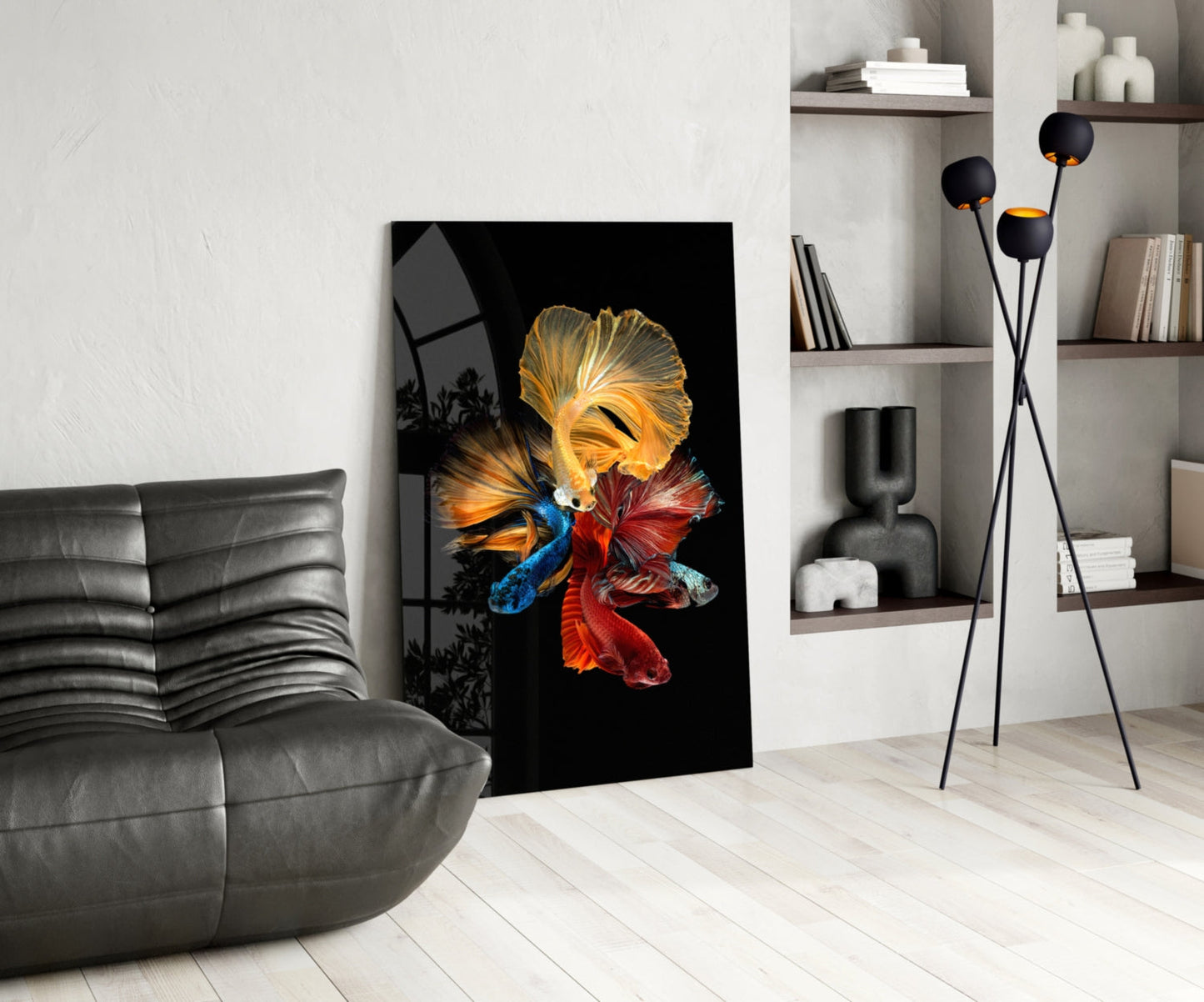 Modern living room displaying colorful betta fish glass wall art on black background, leaning against white wall beside gray sofa.