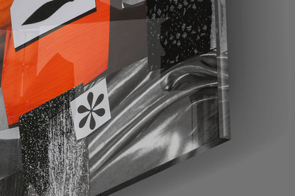 Close-up angled view of glass wall art with orange geometric shapes, black flower symbol, and textured black surface detail.