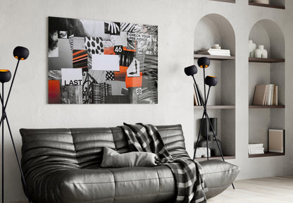 Modern living room featuring black leather sofa with gray throw blanket, black floor lamp with orange accents, and abstract mixed-media wall art with orange, black, and white collage elements above sofa.