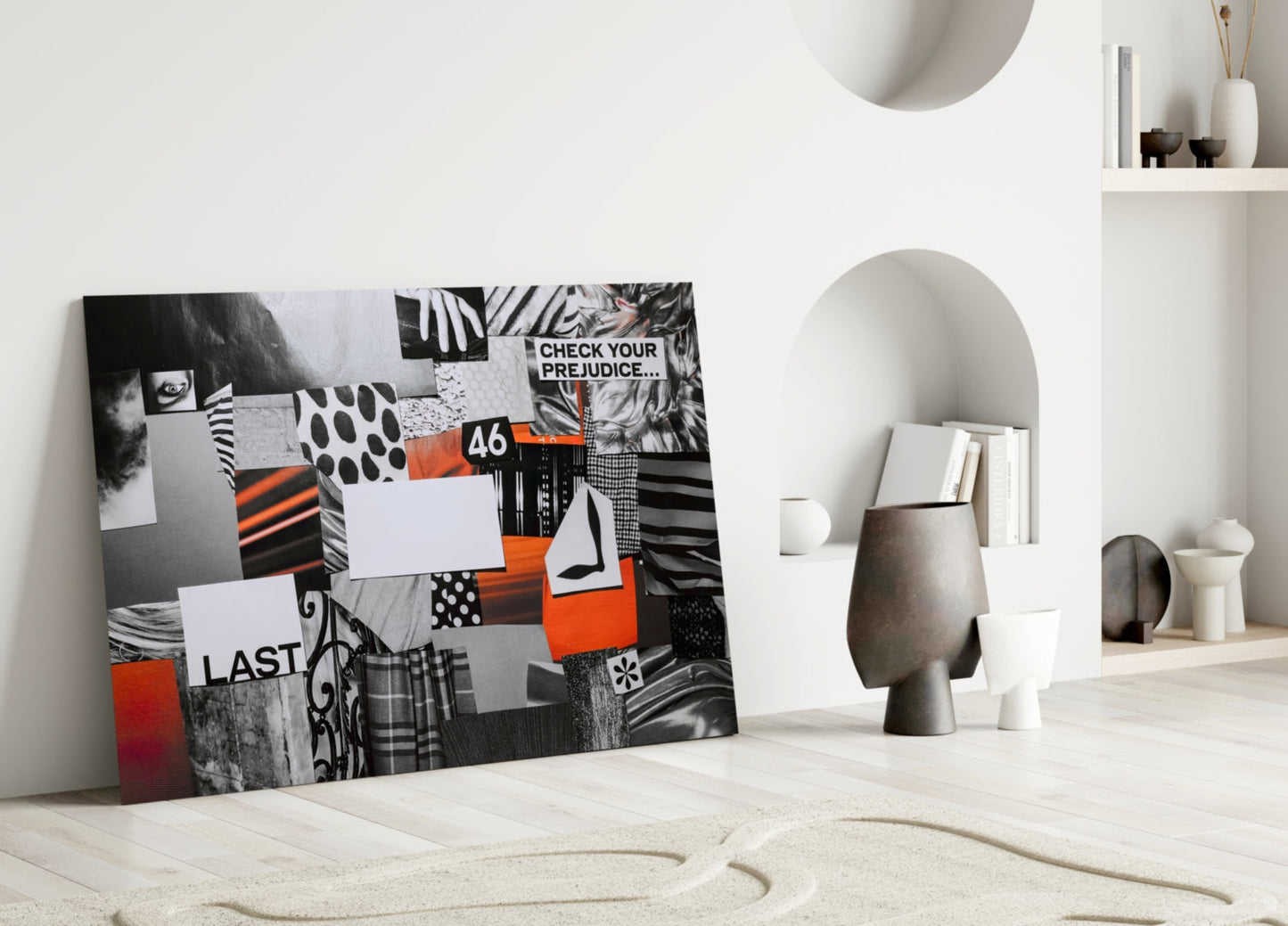 Modern interior display showing black, white, and orange glass wall art leaning against white shelving with decorative objects.