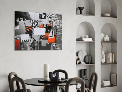 Collage-style glass wall art featuring black, white, and orange geometric patterns with text including "CHECK YOUR PREJUDICE" and "LAST" displayed above a round dining table.