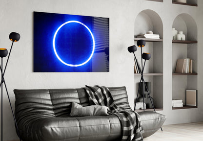 Blue neon circle glass wall art displayed above gray leather sofa in modern living room interior.