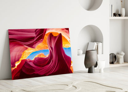 Vibrant glass wall art leaning against white wall displays swirling magenta, orange, and blue canyon-inspired patterns in minimalist room setting.