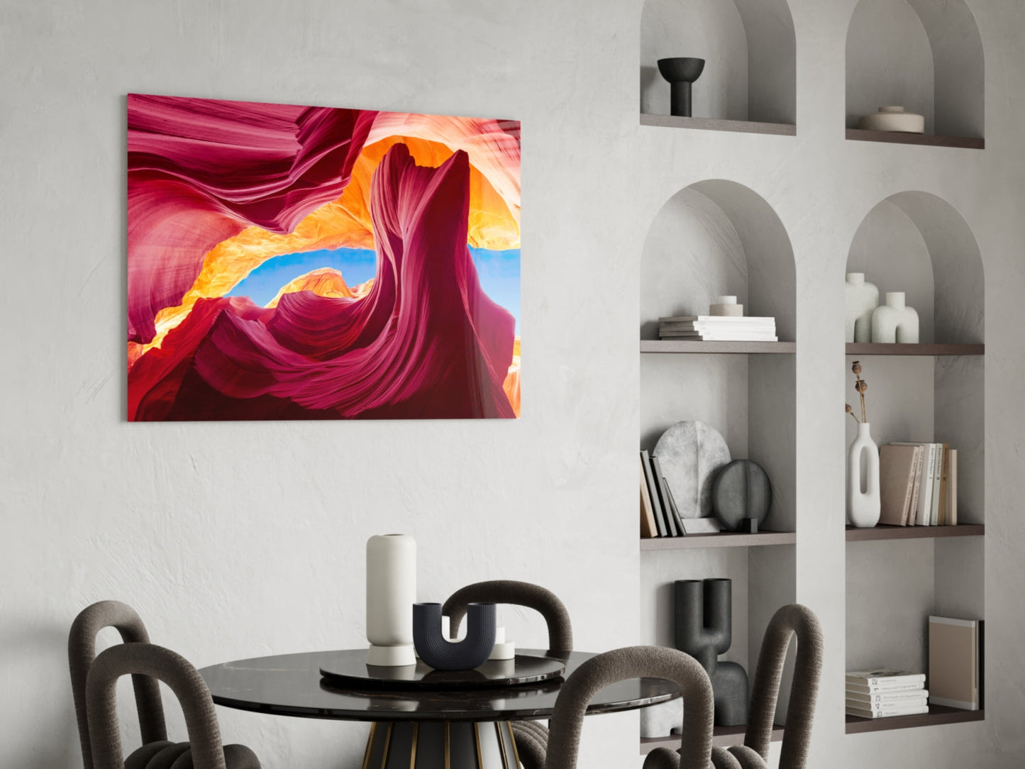 Red Valley glass wall art displaying vibrant pink, orange, and blue canyon swirls hung above a round black dining table.
