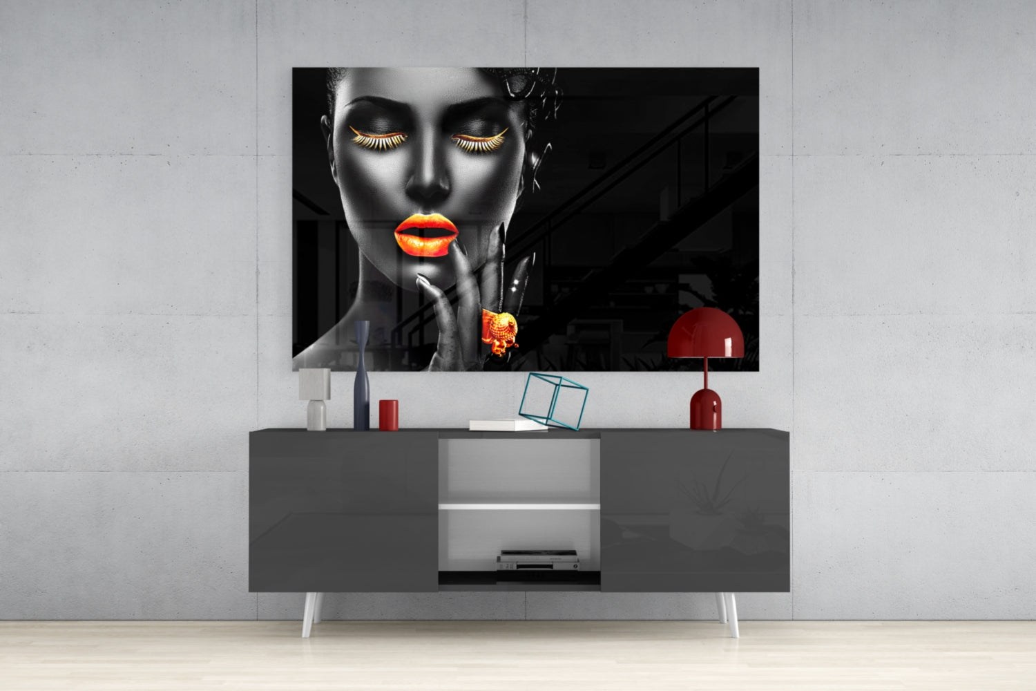 Modern living room setup featuring a gray media console displaying a black and white portrait with glowing orange lips and eyelashes, styled with red decorative accessories.