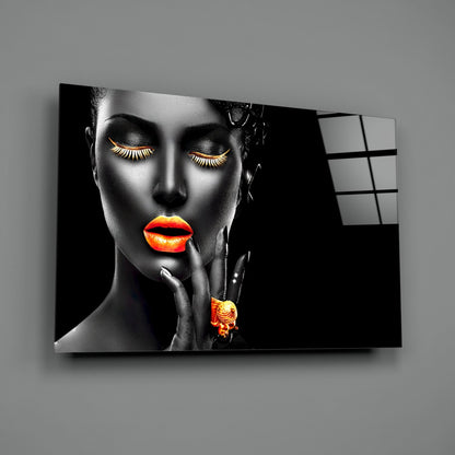 Black and white portrait with neon orange lips and eyelashes on glass wall art, mounted at an angle against gray wall.