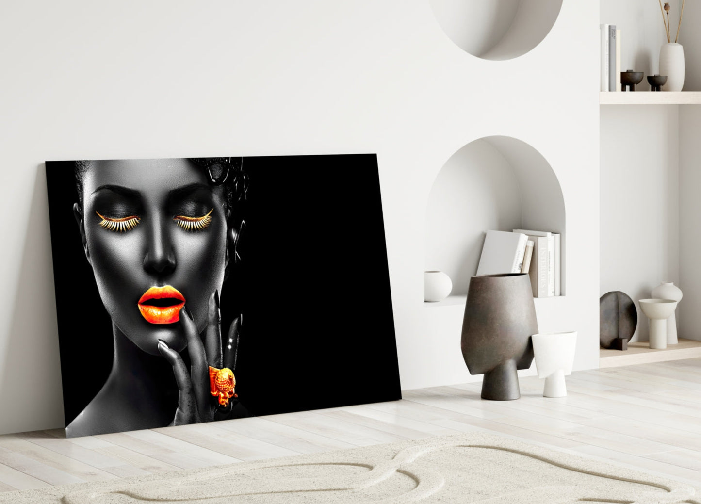 Modern glass art featuring a black face with gold eyelashes and vibrant orange lips and earring, displayed in a minimalist white room setting.