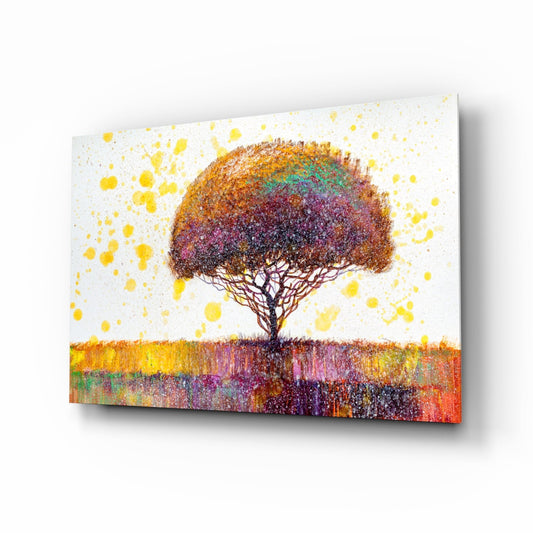 Angled view of a glass wall art panel depicting a solitary tree with colorful speckled foliage against a white sky with yellow splatters and vibrant ground.