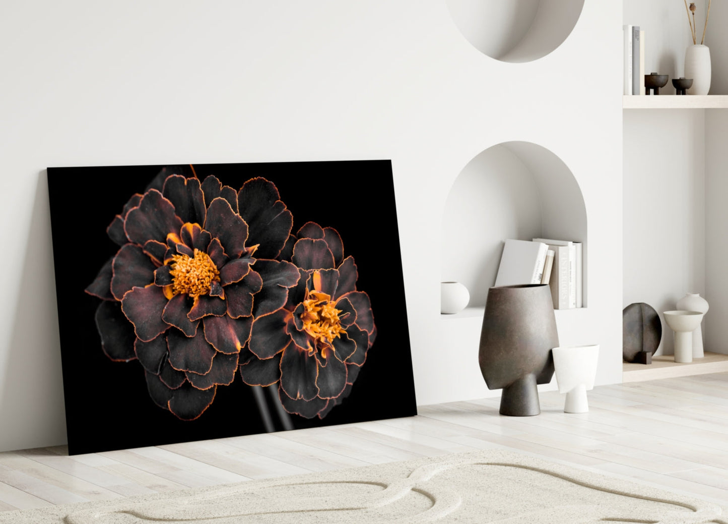 Brown flower glass wall art leaning against white wall in minimalist room setting with decorative objects.