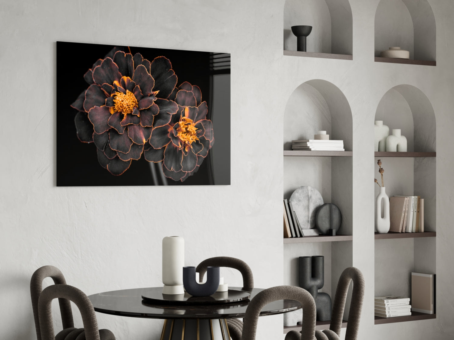 Brown flower glass wall art with golden centers displayed above a black dining table in a modern white interior.