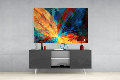Colorful abstract fractal flower glass wall art with radiating yellow, orange, red, and blue rays displayed above a dark gray media console.