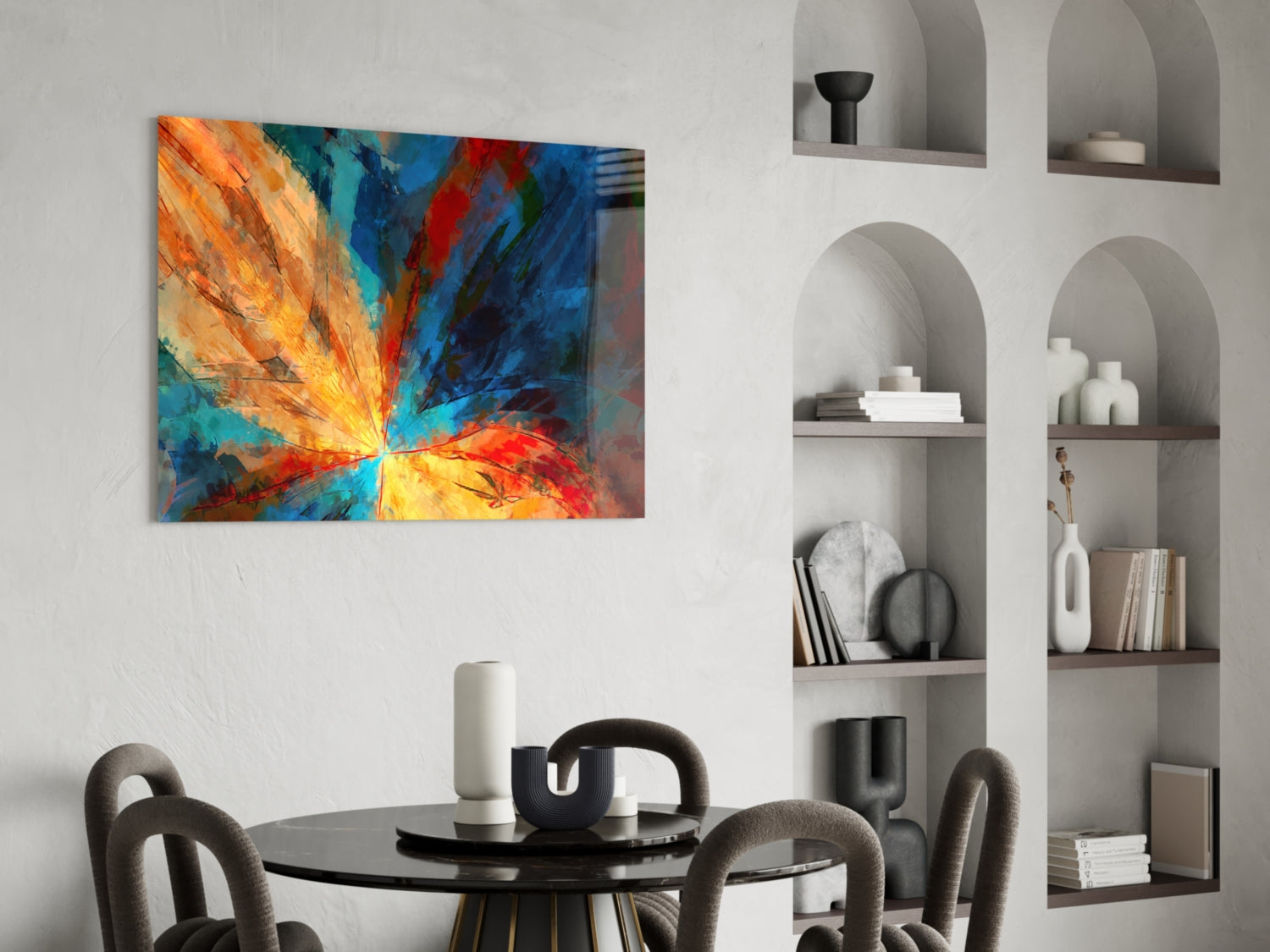 Vibrant abstract fractal flower glass art with orange, yellow, blue and red radiating rays displayed above a modern dining table.