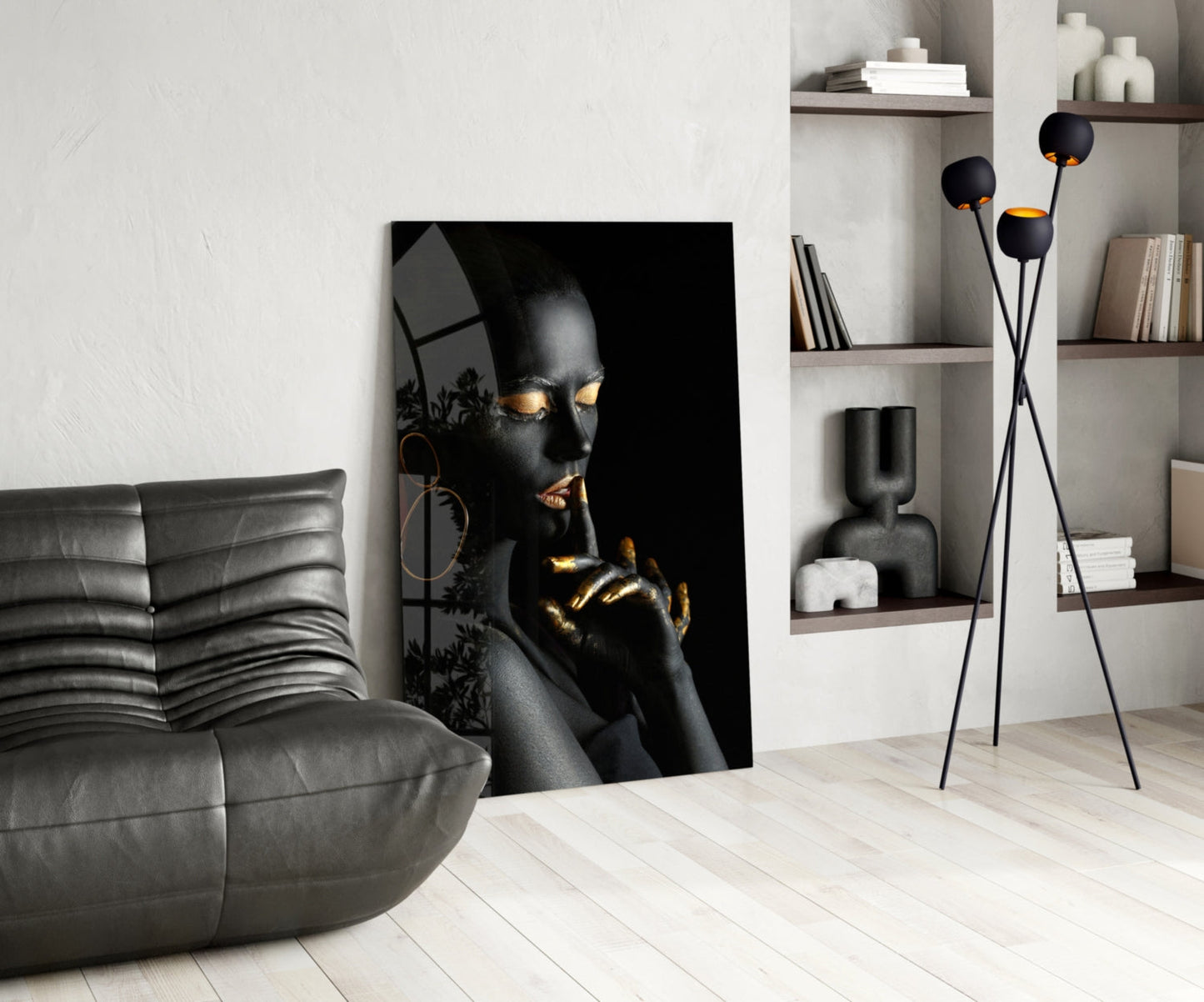 Black and gold portrait glass art displayed in modern living room with gray sofa and wall shelving.