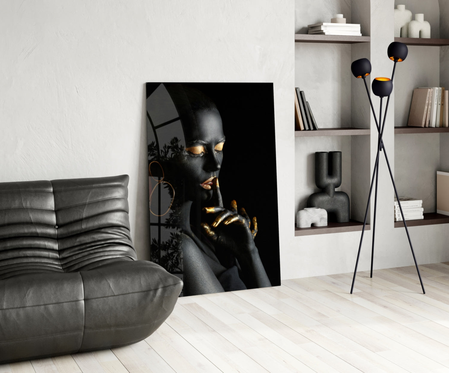 Black and gold portrait glass art displayed in modern living room with gray sofa and wall shelving.