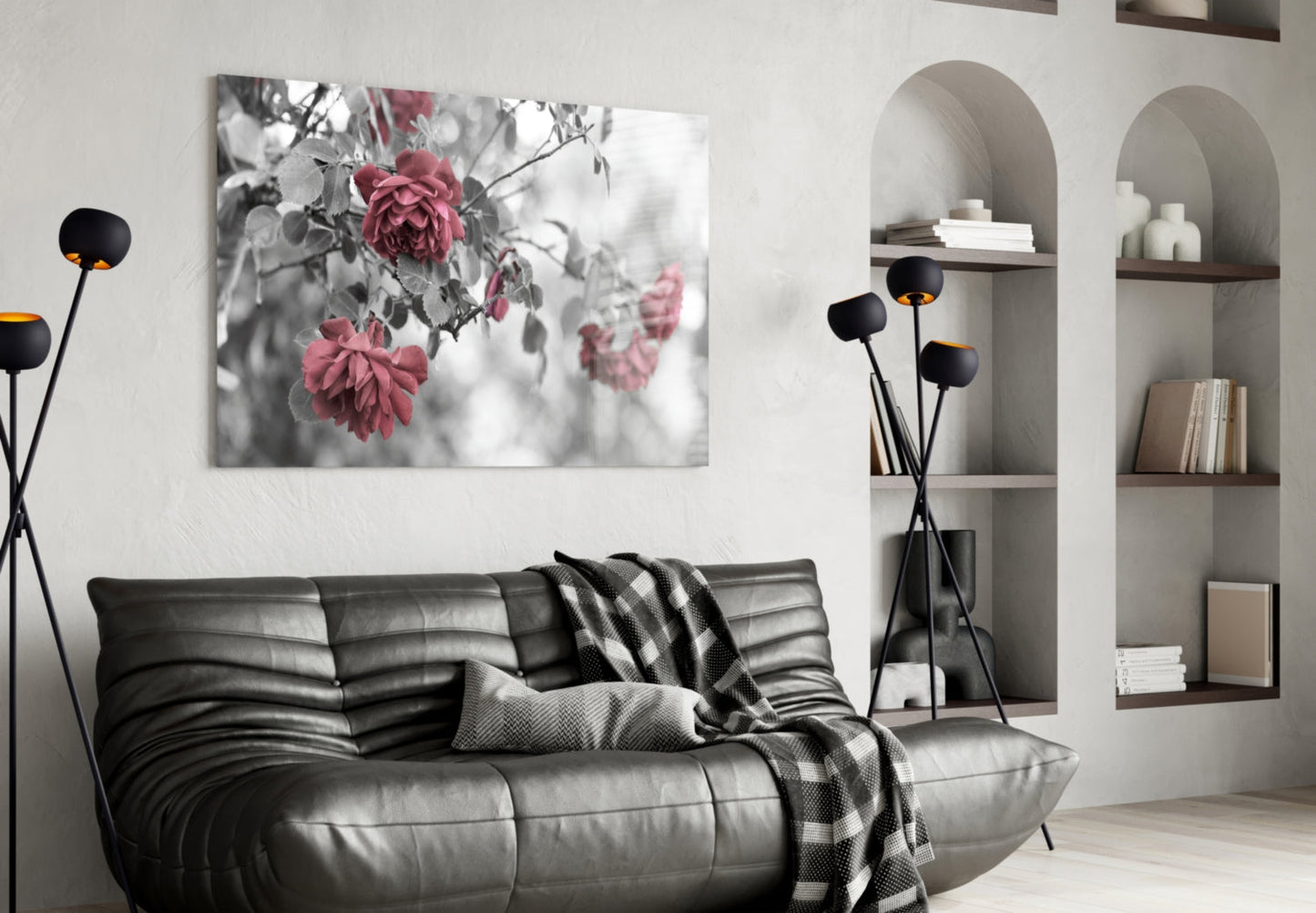 Black and white rose photograph with pink accent flowers displayed above gray leather sofa in modern living room.