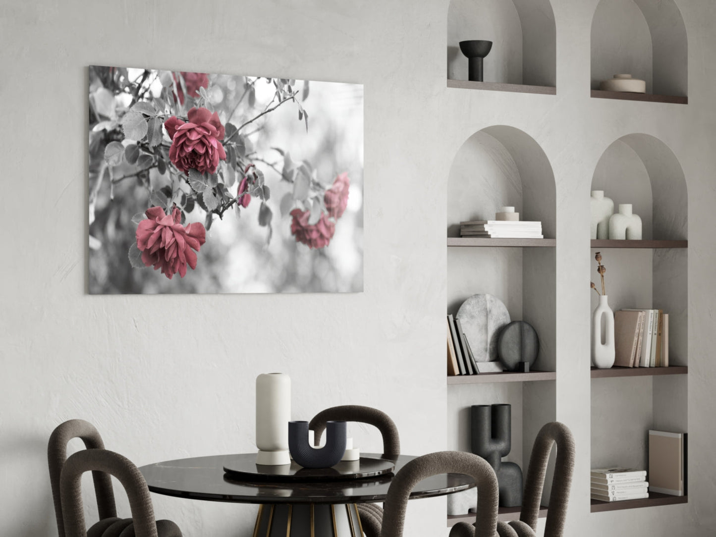 Pink roses glass wall art displaying red flowers on gray branches above a round black dining table with chairs.