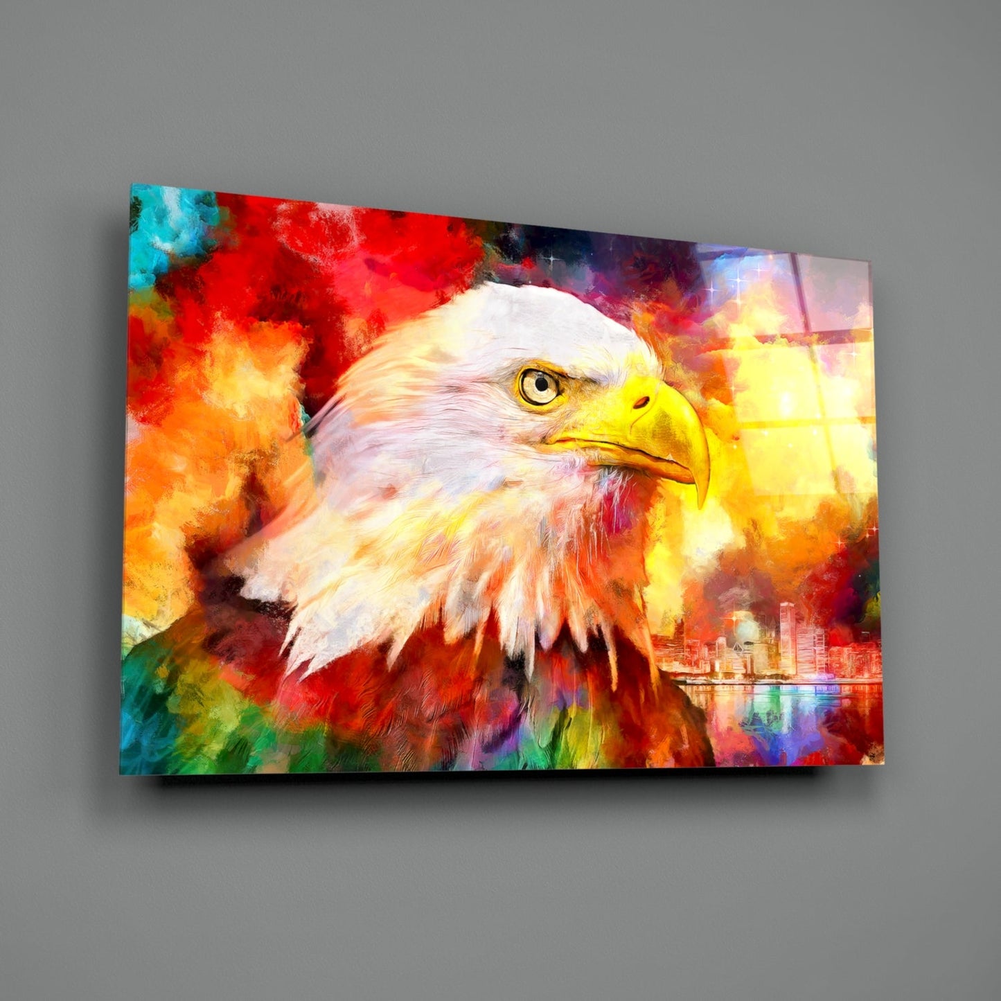Colorful glass wall art displaying a bald eagle's head against vibrant red, yellow, orange, and blue watercolor-style background with cityscape reflection.