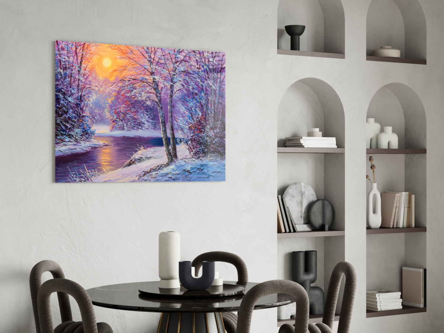 Colorful winter landscape glass art depicting a snowy forest path with purple trees and golden sunset, displayed above a round dining table in a modern interior.